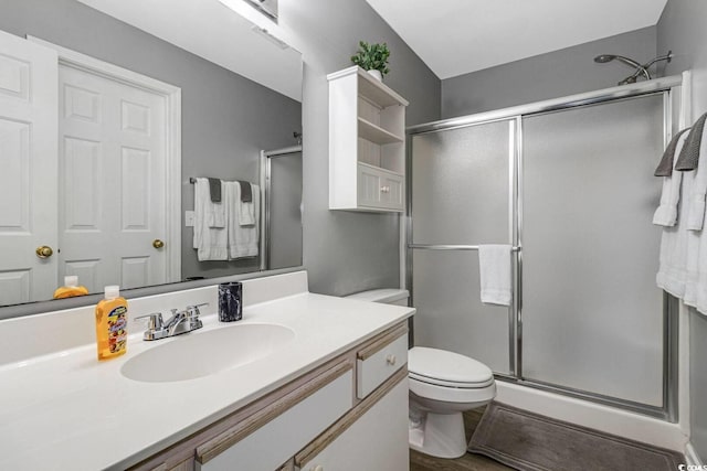 bathroom featuring a shower stall, toilet, and vanity