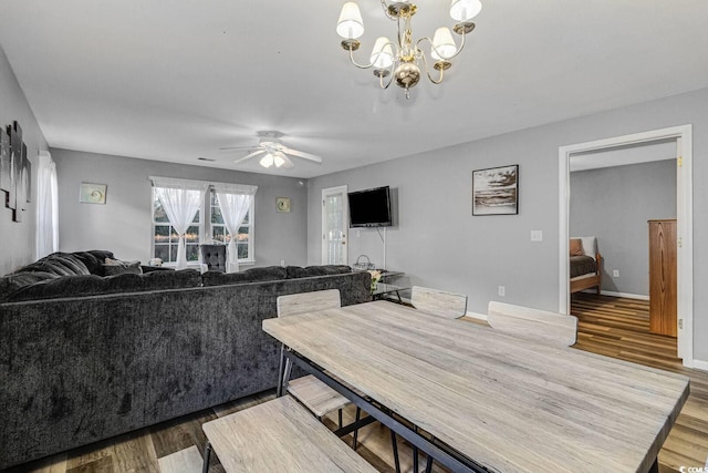 dining area featuring ceiling fan with notable chandelier, wood finished floors, and baseboards