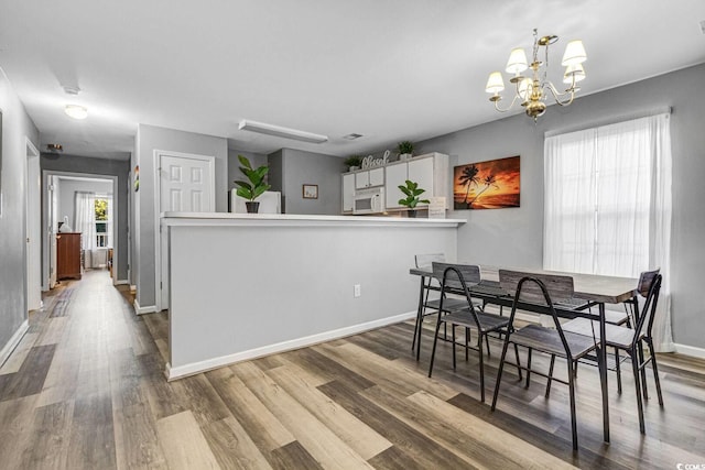 dining space featuring an inviting chandelier, baseboards, and wood finished floors