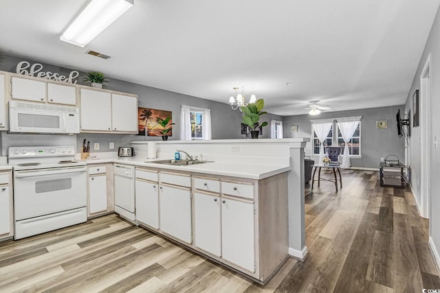 kitchen with white appliances, visible vents, a peninsula, light countertops, and a sink