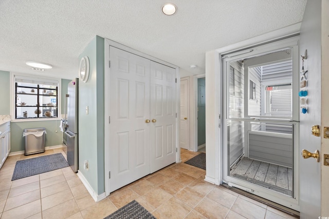 bathroom with baseboards, a textured ceiling, and tile patterned floors