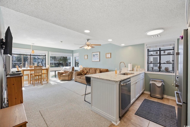 kitchen with visible vents, appliances with stainless steel finishes, a breakfast bar, light stone countertops, and a sink