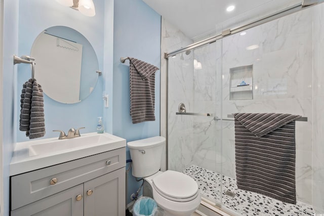 bathroom with a marble finish shower, vanity, and toilet