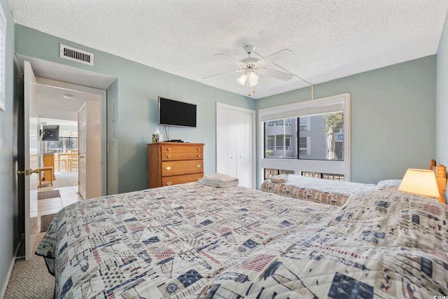 bedroom with a textured ceiling, a closet, visible vents, and a ceiling fan