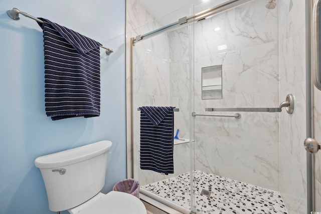 bathroom featuring a marble finish shower and toilet