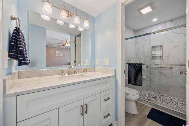 full bathroom featuring toilet, a marble finish shower, wood finished floors, and vanity