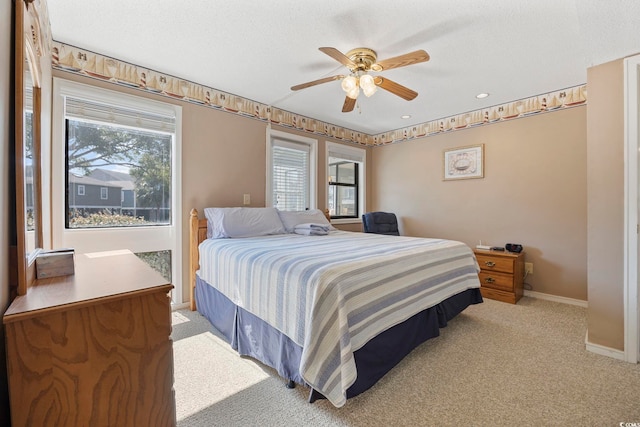 bedroom with light carpet, multiple windows, baseboards, and a textured ceiling