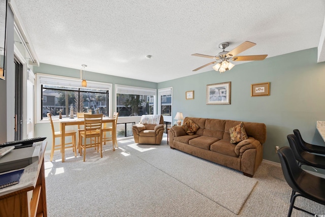 carpeted living area featuring a ceiling fan, a textured ceiling, and baseboards