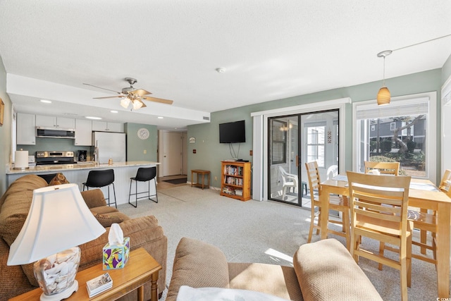 living room with a ceiling fan, light carpet, and baseboards