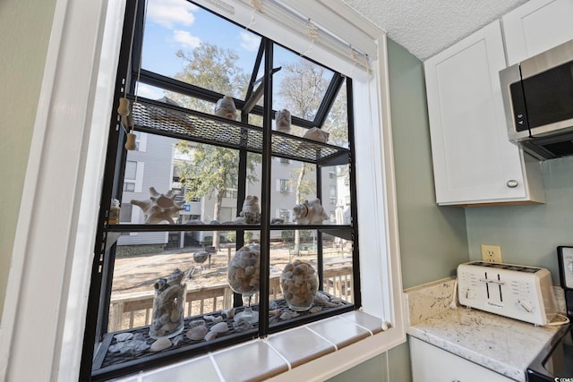 details with a toaster, stainless steel microwave, and a textured ceiling