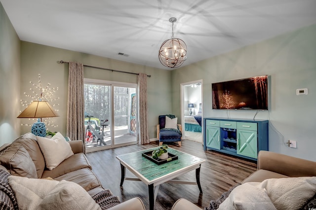 living area with a notable chandelier, visible vents, and wood finished floors