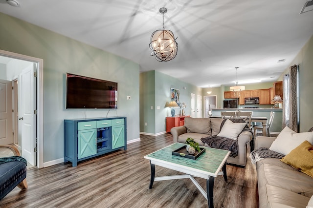 living room with an inviting chandelier, visible vents, baseboards, and wood finished floors