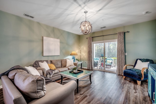 living room with baseboards, a notable chandelier, visible vents, and wood finished floors