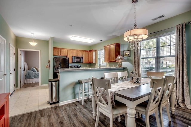 dining room featuring baseboards, a notable chandelier, visible vents, and light wood-style floors