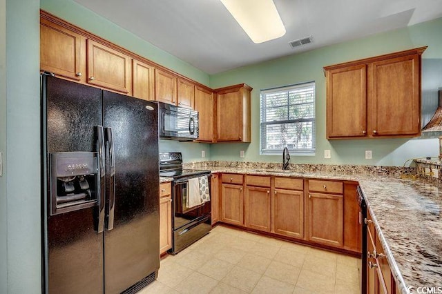 kitchen featuring black appliances, visible vents, brown cabinets, and a sink