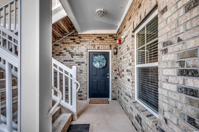 property entrance with a porch and brick siding