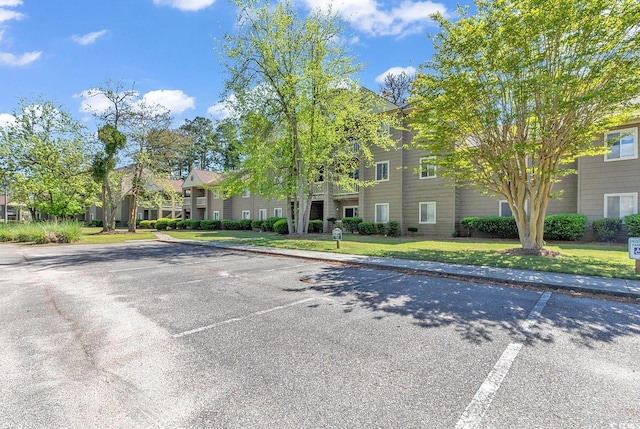 exterior space featuring uncovered parking and a front lawn