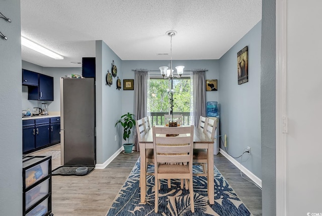 dining area featuring light wood-style floors, baseboards, a chandelier, and a textured ceiling