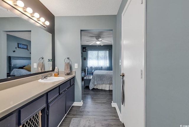 bathroom featuring a textured ceiling, ceiling fan, connected bathroom, wood finished floors, and vanity