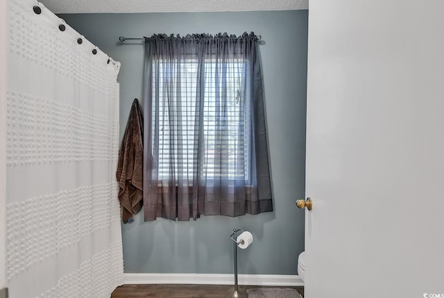 bathroom with a shower with shower curtain, toilet, and baseboards