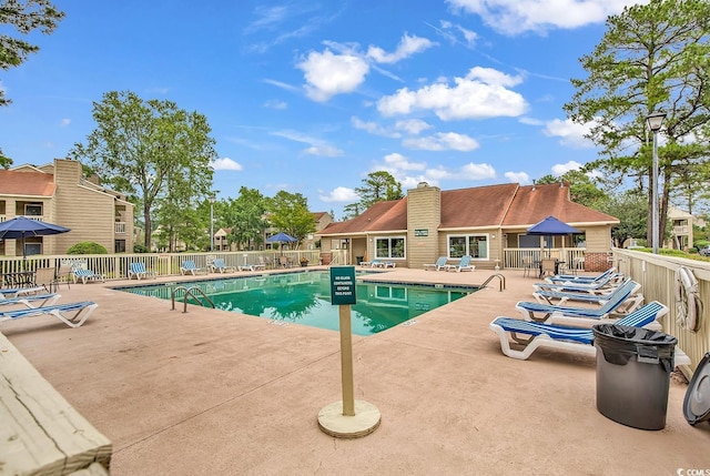 community pool with a patio and fence