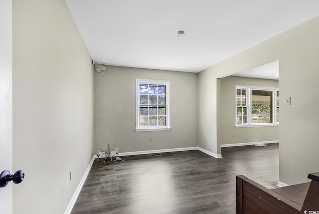 spare room with dark wood-style floors, a wealth of natural light, and baseboards
