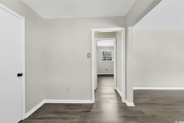 empty room featuring baseboards and dark wood-type flooring