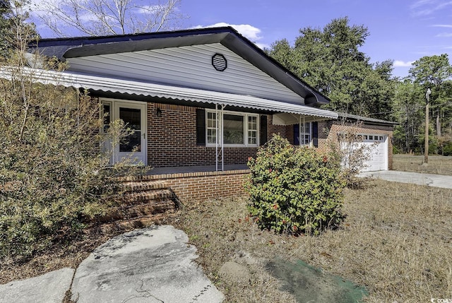 view of front of home featuring covered porch, brick siding, driveway, and an attached garage