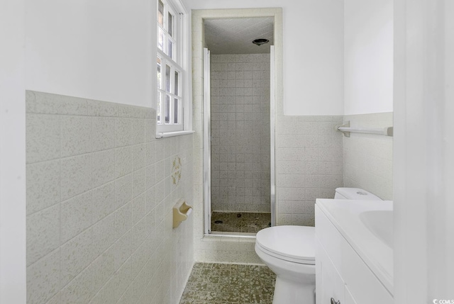 bathroom with toilet, a stall shower, tile walls, and wainscoting