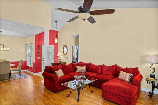 living room featuring high vaulted ceiling, wood finished floors, a ceiling fan, baseboards, and decorative columns