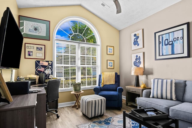 office space with a textured ceiling, baseboards, vaulted ceiling, and wood finished floors