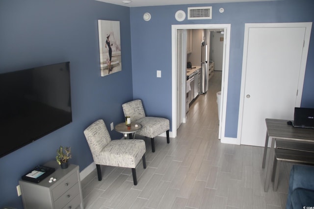 living area featuring wood finish floors, visible vents, and baseboards