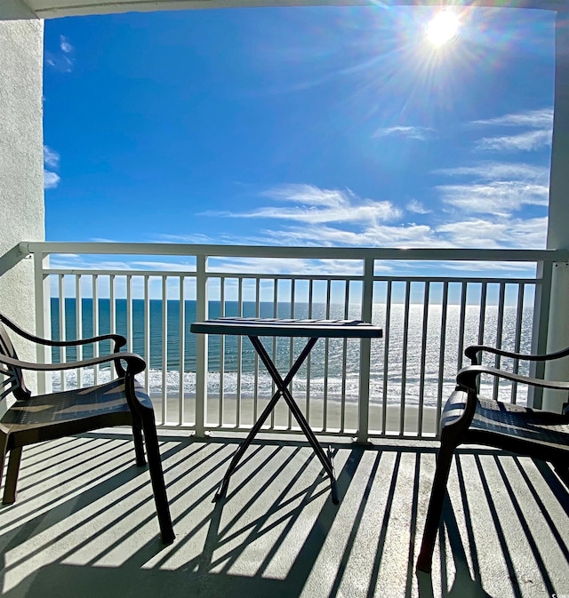 balcony featuring a view of the beach and a water view