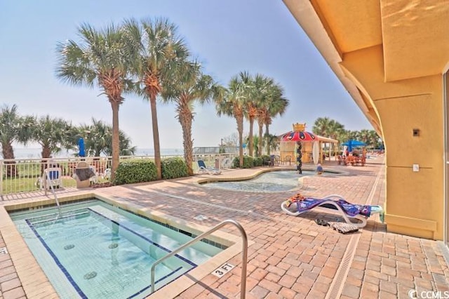 view of pool with fence, a hot tub, and a patio