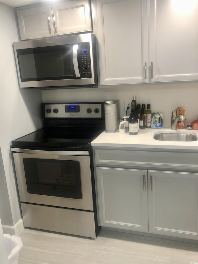 kitchen with appliances with stainless steel finishes, light countertops, and a sink