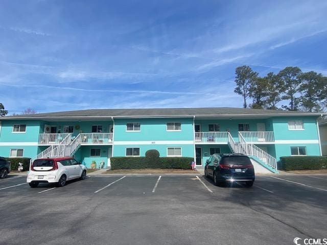 view of property featuring uncovered parking and stairway