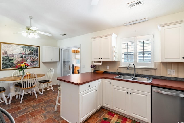 kitchen with visible vents, white cabinets, dark countertops, stainless steel dishwasher, and a sink