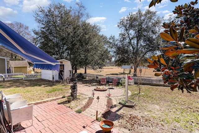 view of yard with a fire pit, a patio area, fence, and an outdoor structure