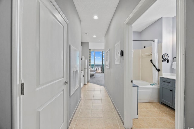 hallway with recessed lighting, baseboards, a textured ceiling, and light tile patterned flooring