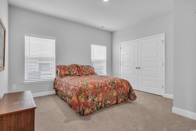 carpeted bedroom with visible vents, baseboards, and a closet