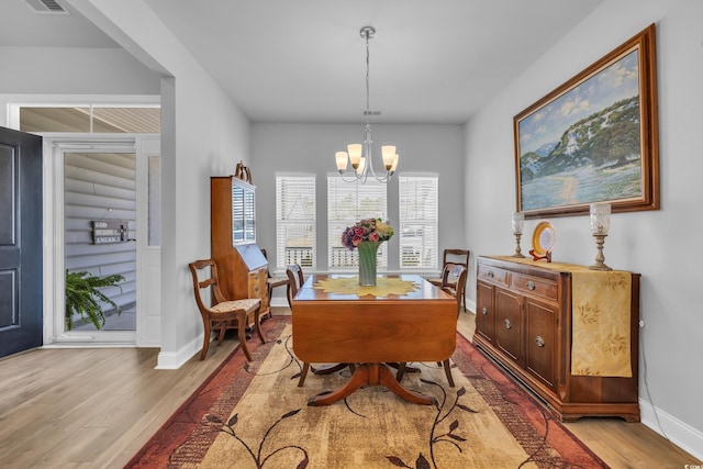 dining area featuring baseboards, light wood-style floors, visible vents, and an inviting chandelier