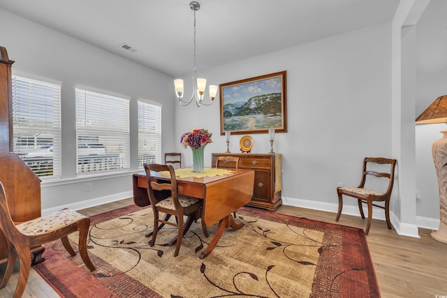 dining area featuring light wood-type flooring, an inviting chandelier, visible vents, and baseboards