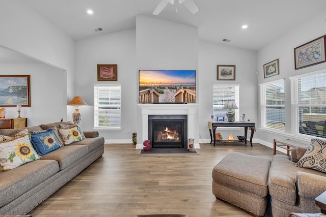 living room with lofted ceiling, recessed lighting, a fireplace with flush hearth, wood finished floors, and visible vents