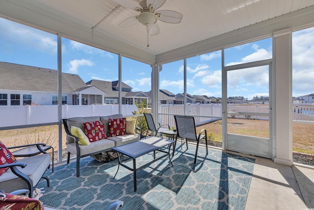 sunroom featuring a ceiling fan, a residential view, and a healthy amount of sunlight