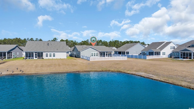 rear view of property with a sunroom, a residential view, fence, and a lawn