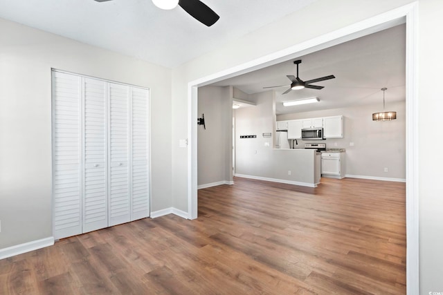 unfurnished living room featuring ceiling fan, light wood finished floors, and baseboards