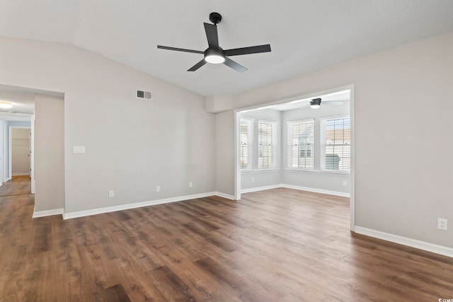 spare room with lofted ceiling, dark wood-type flooring, visible vents, and baseboards