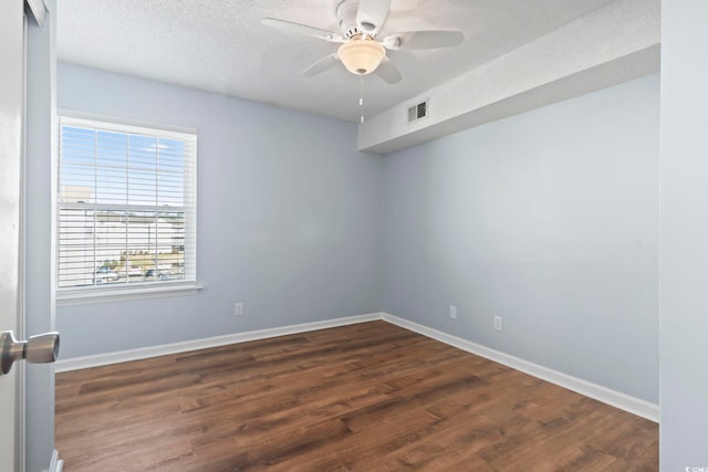 empty room featuring ceiling fan, a textured ceiling, visible vents, baseboards, and dark wood finished floors