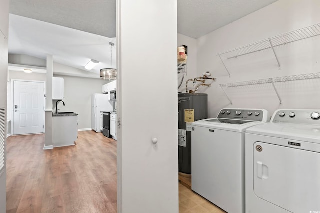 laundry room with washer and clothes dryer, water heater, a sink, laundry area, and baseboards