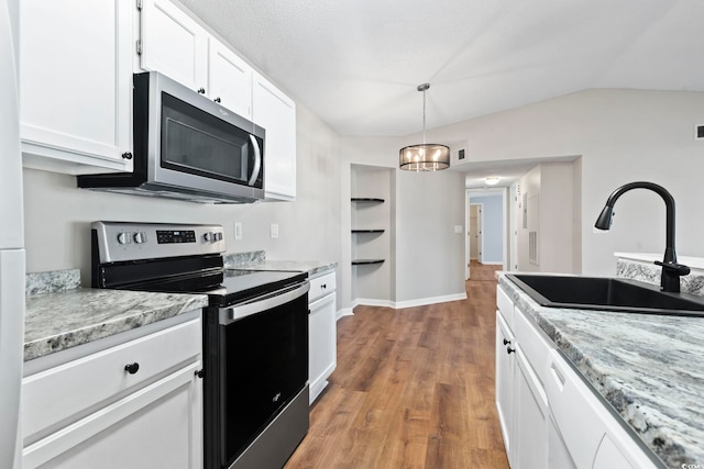 kitchen featuring light wood finished floors, white cabinets, appliances with stainless steel finishes, light stone countertops, and a sink